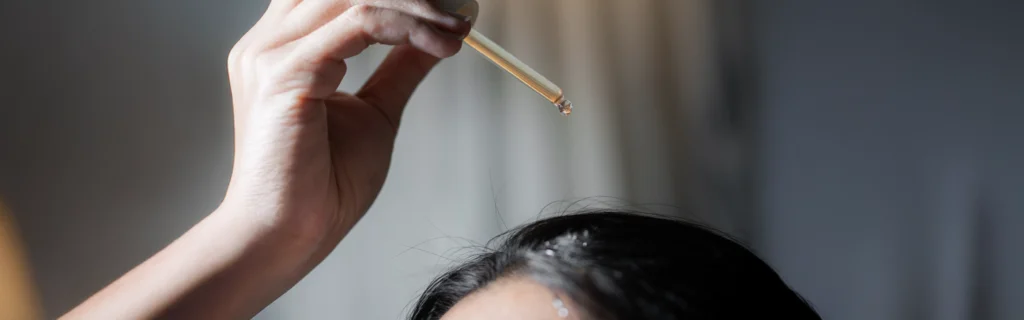 Femme en train d'appliquer de l'huile sur les racines des cheveux