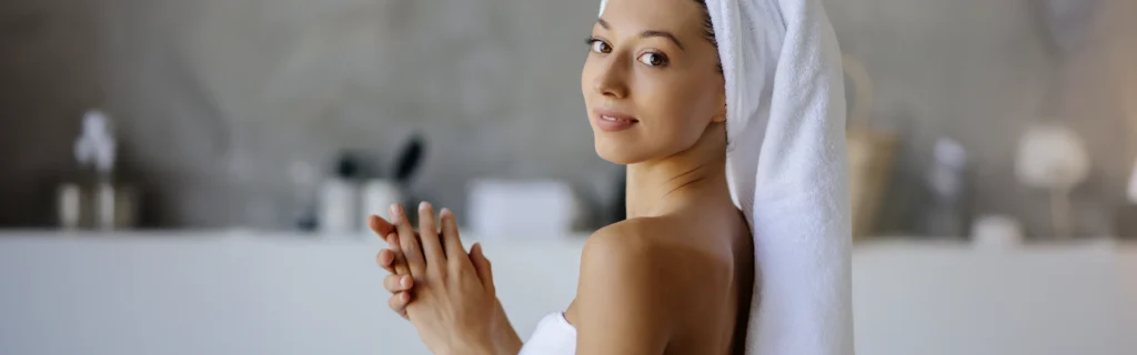 Femme avec une serviette sur la tête réalisant sa routine capillaire