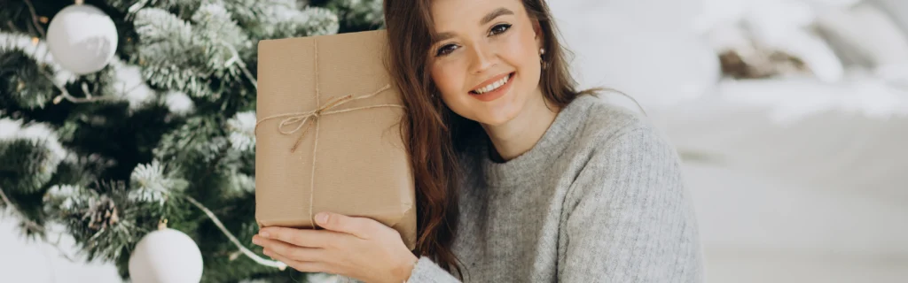 Femme présentant un coffrets de Noël devant un sapin